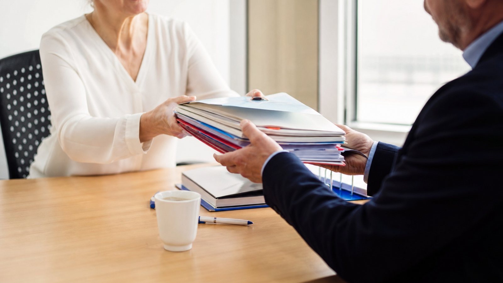 Deux syndics bénévoles passant en revue les dossiers de la copropriété sur une table